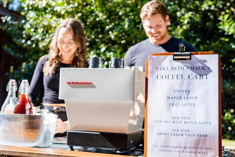 Baristas serving drinks from the Cala Coffee cart with a custom event menu